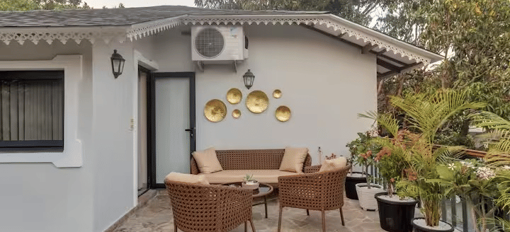 Outdoor seating area with chairs around a table and potted plants towards the side at Lime Tree Villa with Private Pool | Luxury Stay in Goa.